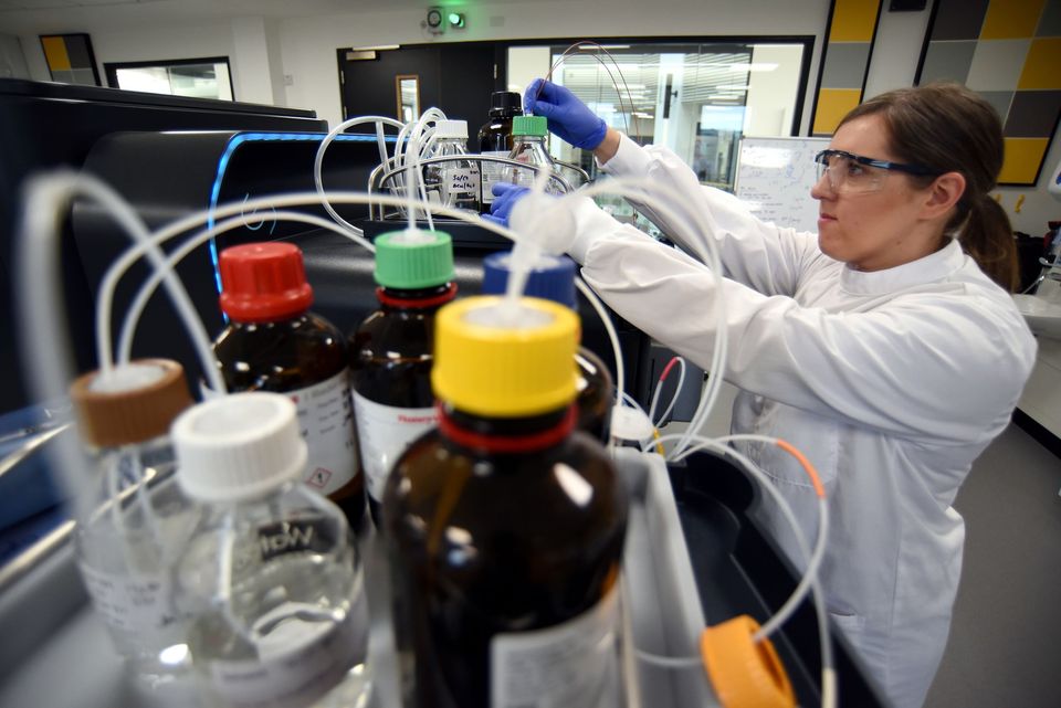 A scientist in a laboratory coat and safety goggles is working with various chemical bottles and equipment. A scientist in a laboratory coat and safety goggles is working with various chemical bottles and equipment.